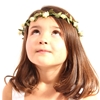 A little girl wearing a white flower crown looks up.