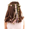 Una bambina dai capelli castani indossa una corona di rose rosa.