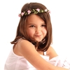 Une fillette en robe blanche porte une couronne de fleurs roses dans ses cheveux bruns
